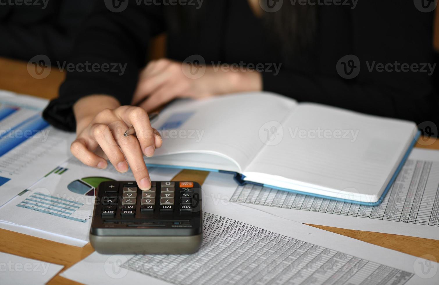 Female makes calculations on a calculator in office with data sheet placed on the desk. photo