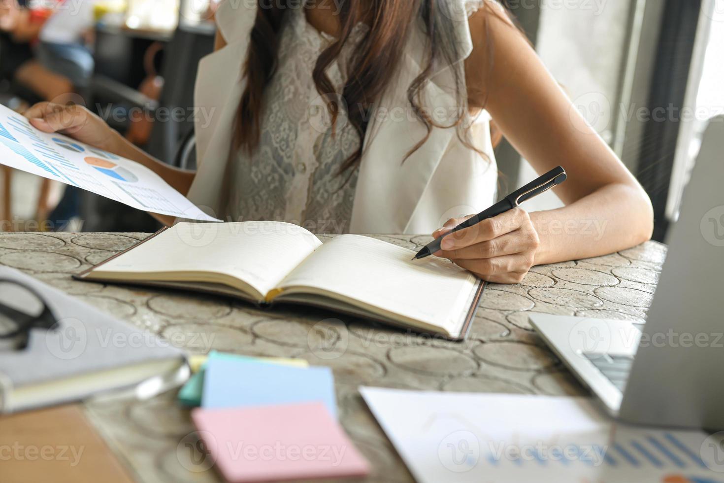 mujeres empresarias están comprobando datos de gráficos y tomando notas en el cuaderno. foto