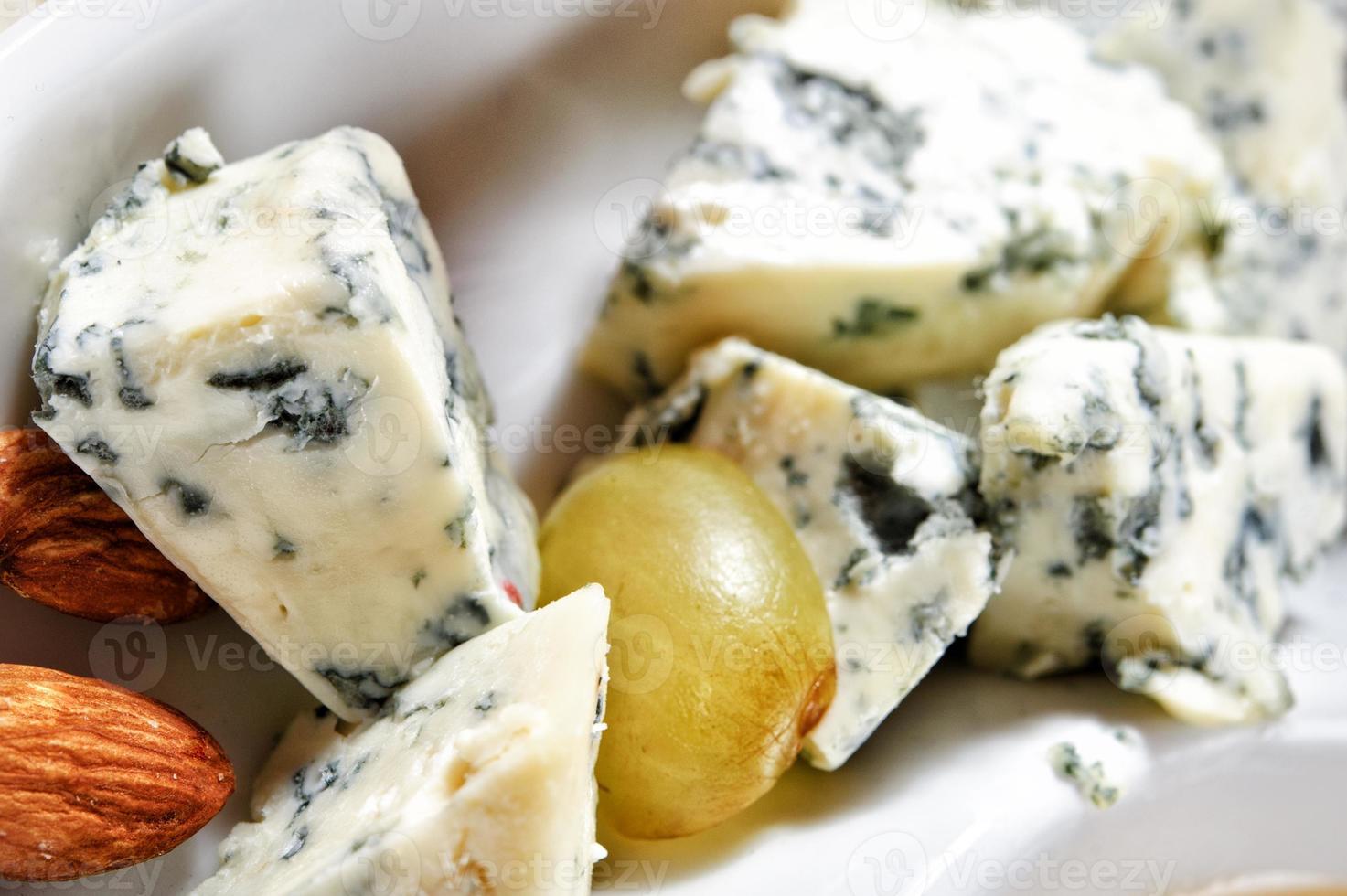 Cheese plate with cheeses Dorblu, Parmesan, Brie, Camembert, Roquefort and grape in serving on the white plate photo