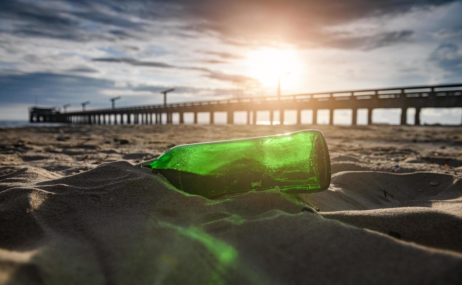 Residuos de botellas de vidrio verde en la playa. foto