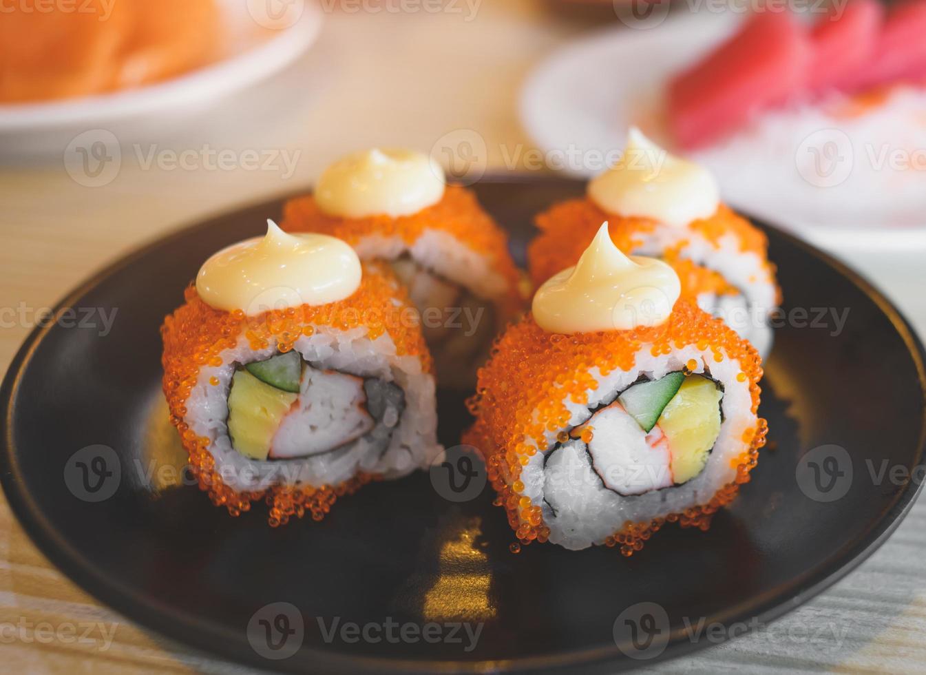 California roll y cortado servido en plato negro. foto