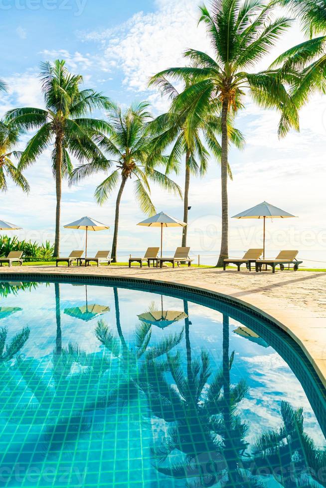 Beautiful luxury umbrella and chair around outdoor swimming pool in hotel and resort with coconut palm tree on sunset  or sunrise sky photo