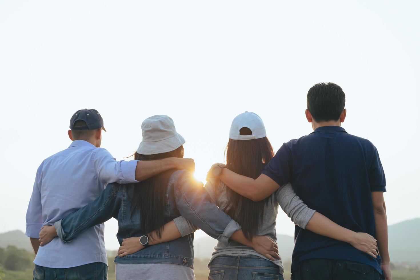 Primer plano de amigos masculinos y femeninos abrazándose mirando el amanecer. conceptos de felicidad, éxito, amistad y comunidad. foto