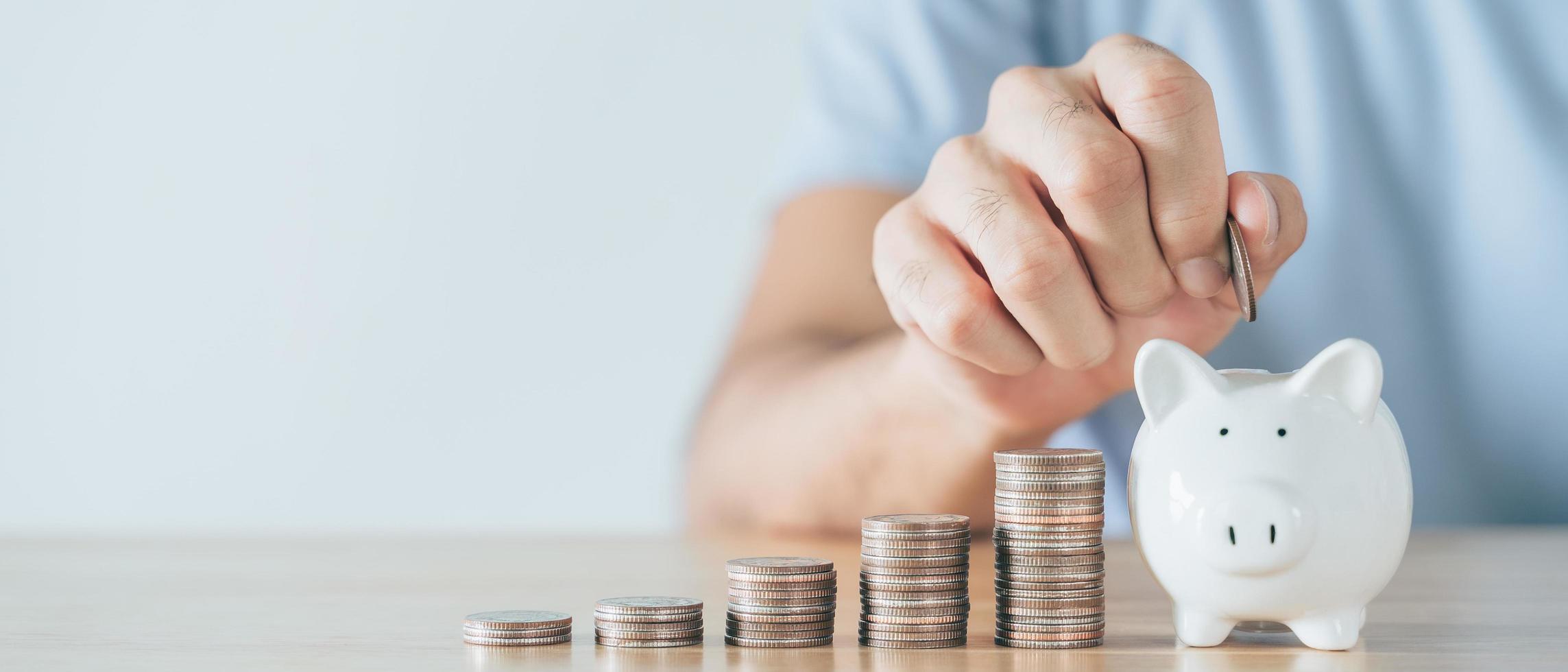 Closeup of man hand putting money coin into piggy bank for saving money. saving money and financial concept photo
