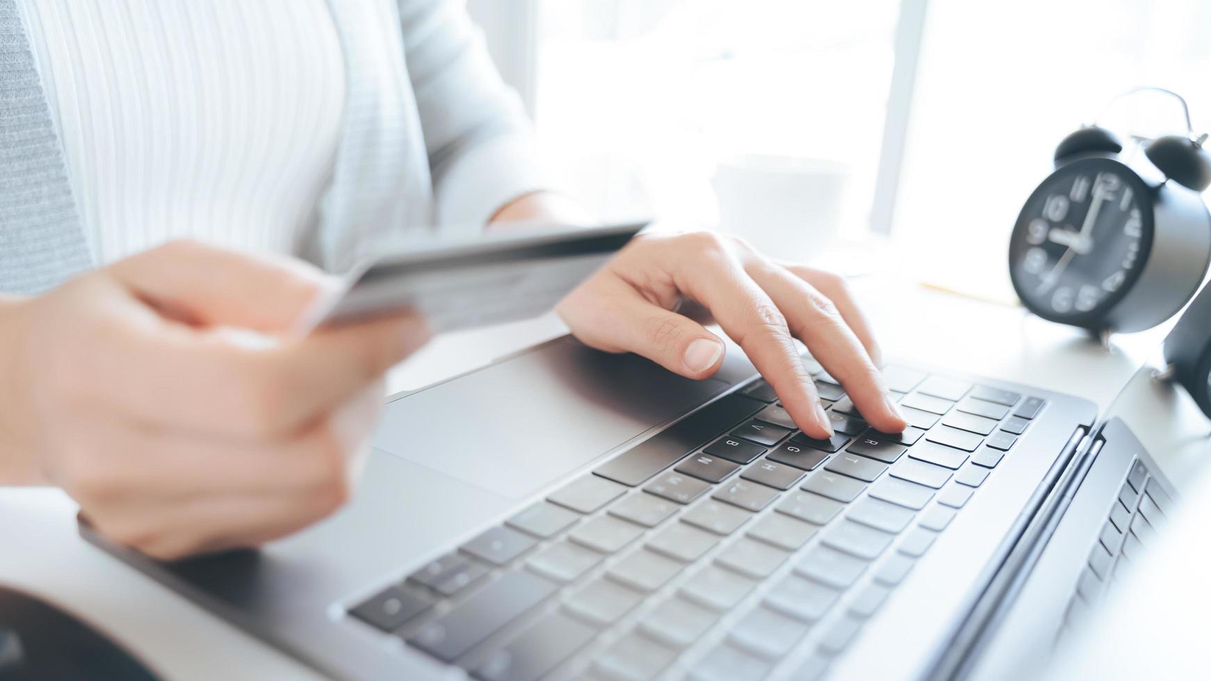 mano de mujer sosteniendo tarjeta de crédito y usando laptop. pago en línea, concepto de compra en línea foto