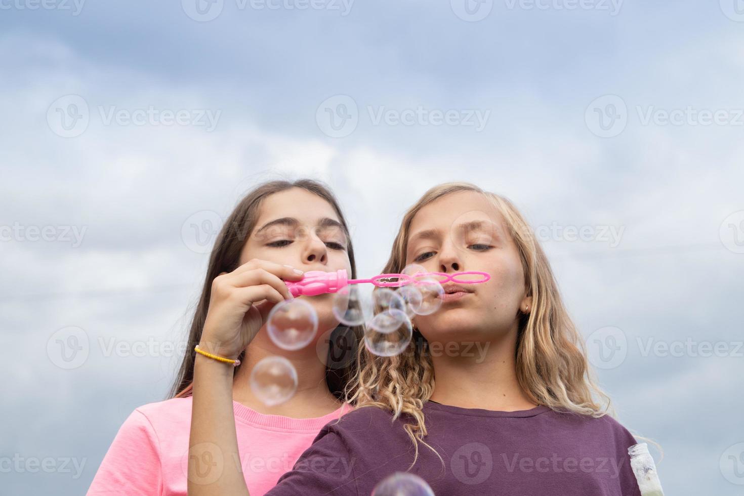 Two girlfriends blowing soap bubbles - carefree and fun time and friendship photo