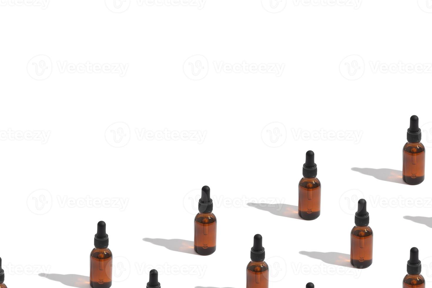 pattern with glass bottle with a dropper for oil or tincture on a white background with copy space. Cosmetics background photo