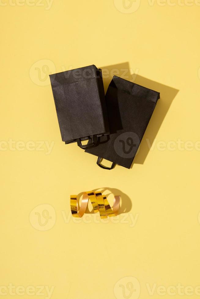 Bolsas de la compra negras en venta de viernes negro plana yacía sobre fondo amarillo con guirnalda festiva foto