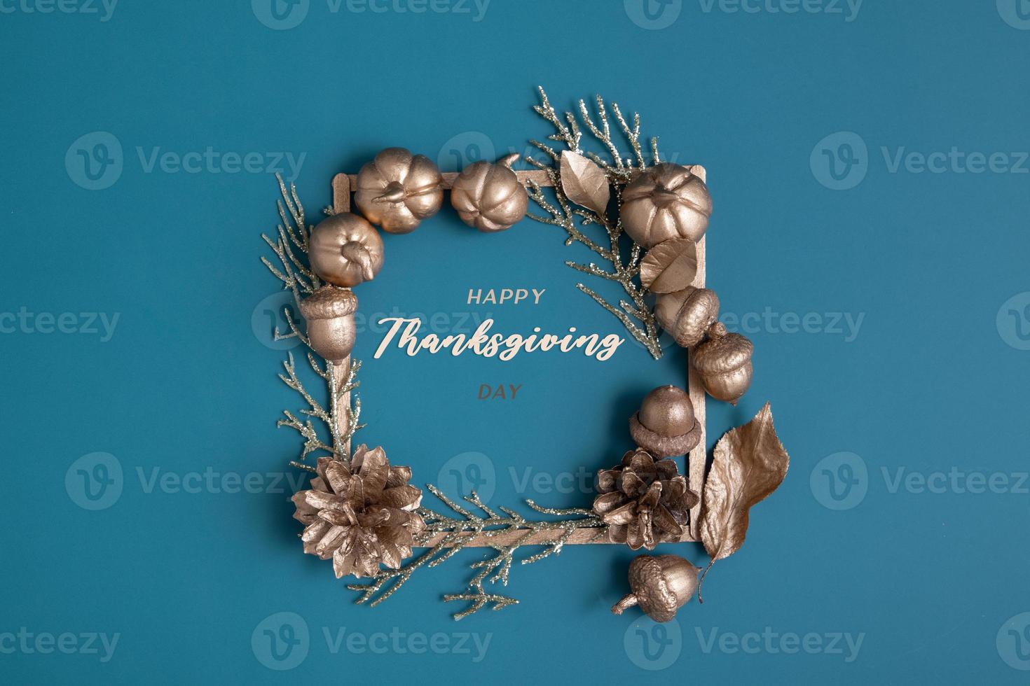 Happy Thanksgiving lettering with flat lay golden pumpkins and acorns on a turquoise background photo