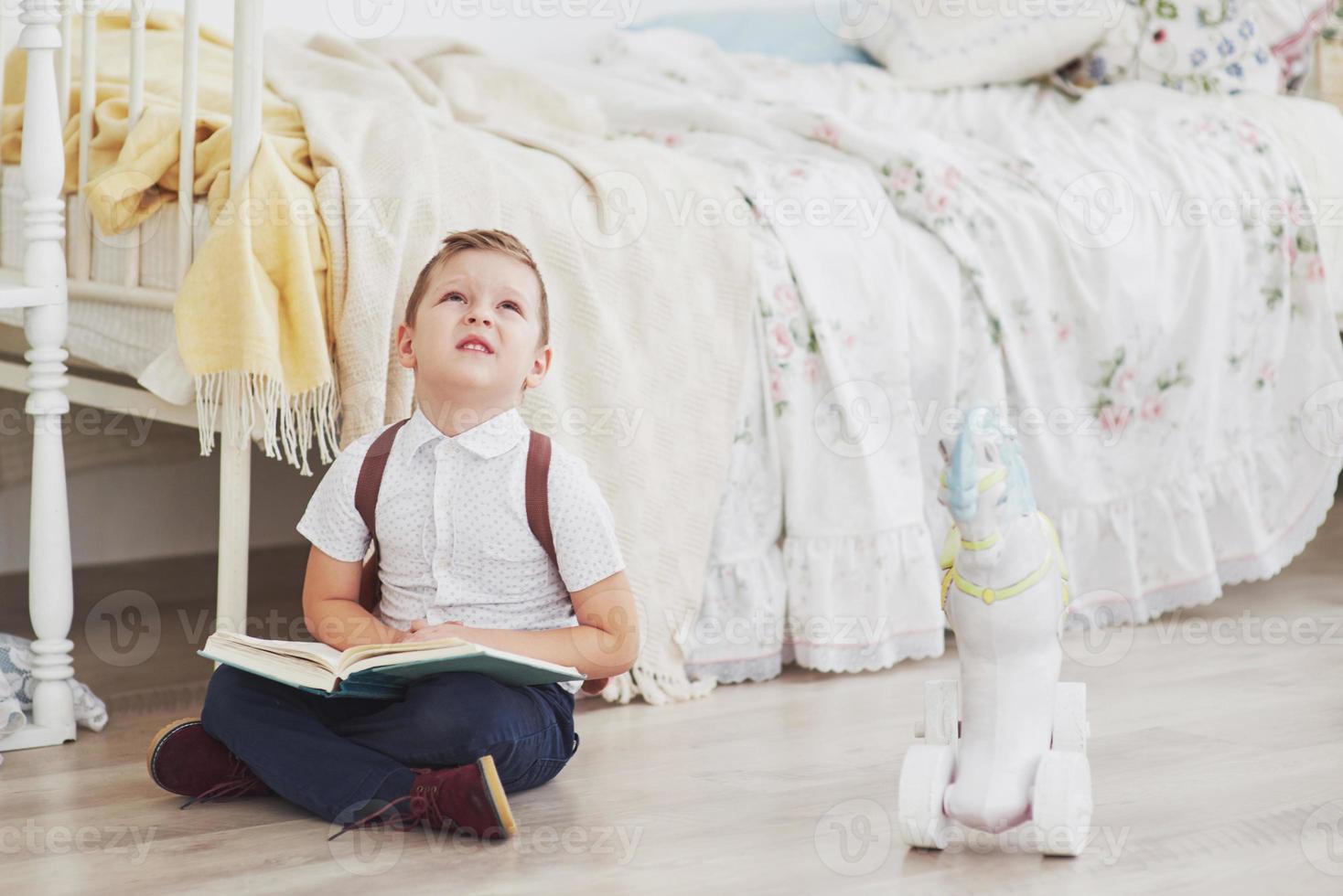 Cute little boy is going to school for the first time. Child with school bag and book. Kid makes a briefcase, child room on a background. Back to school photo