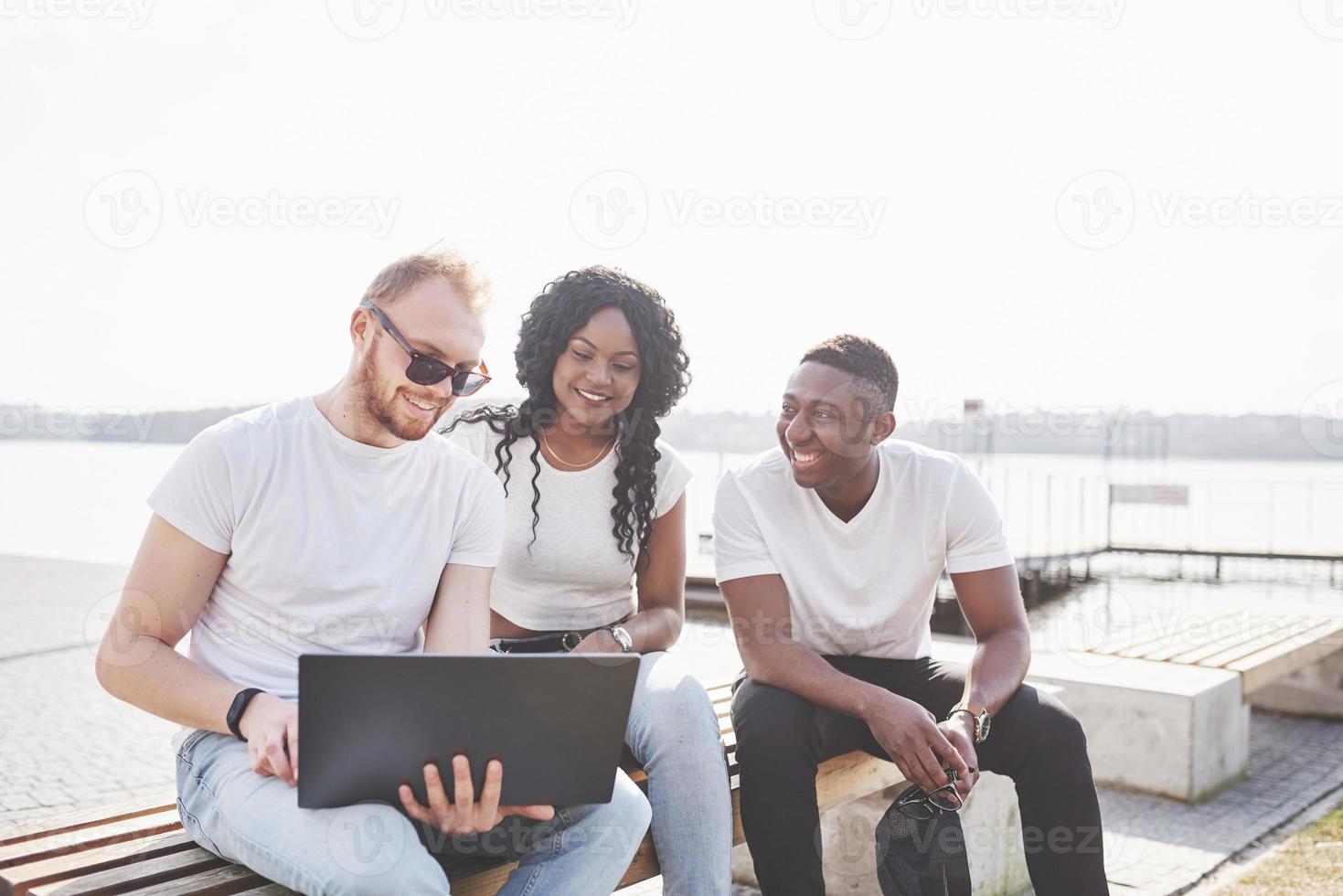 Beautiful multi ethnic friends using a laptop in the Street. Youth lifestyle concept photo