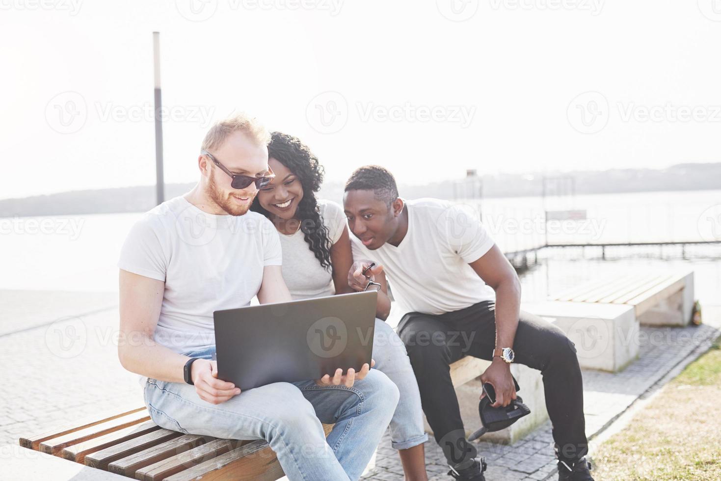 Beautiful multi ethnic friends using a laptop in the Street. Youth lifestyle concept photo