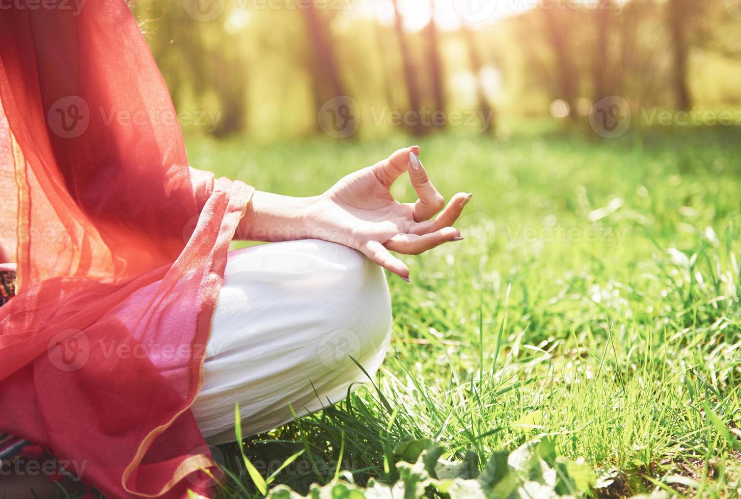 La meditación del yoga en un parque sobre el césped es una mujer sana en reposo foto