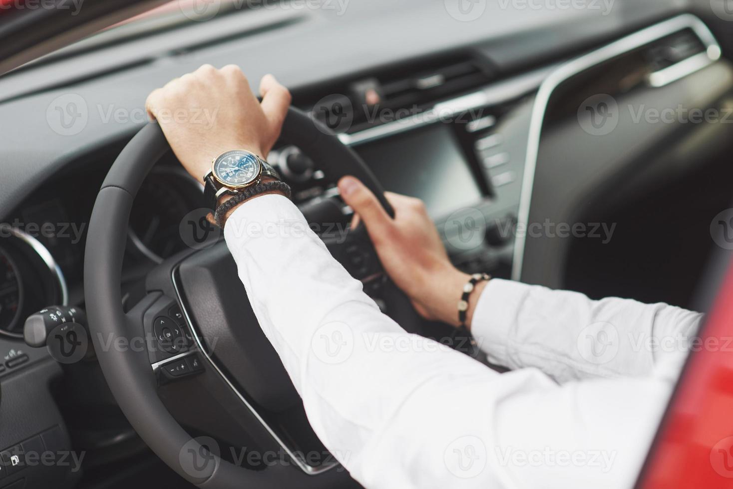 A businessman rides his car, moves on the wheel. A watch on hand in a man's divorce. photo