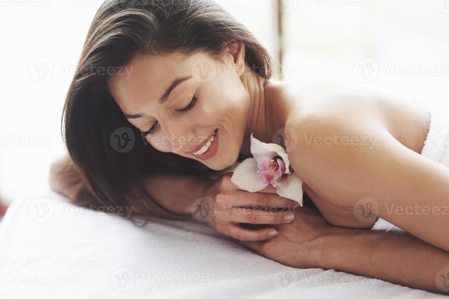 mujer de hermoso cuerpo con orquídea de flor blanca y cuidado del cuerpo. foto