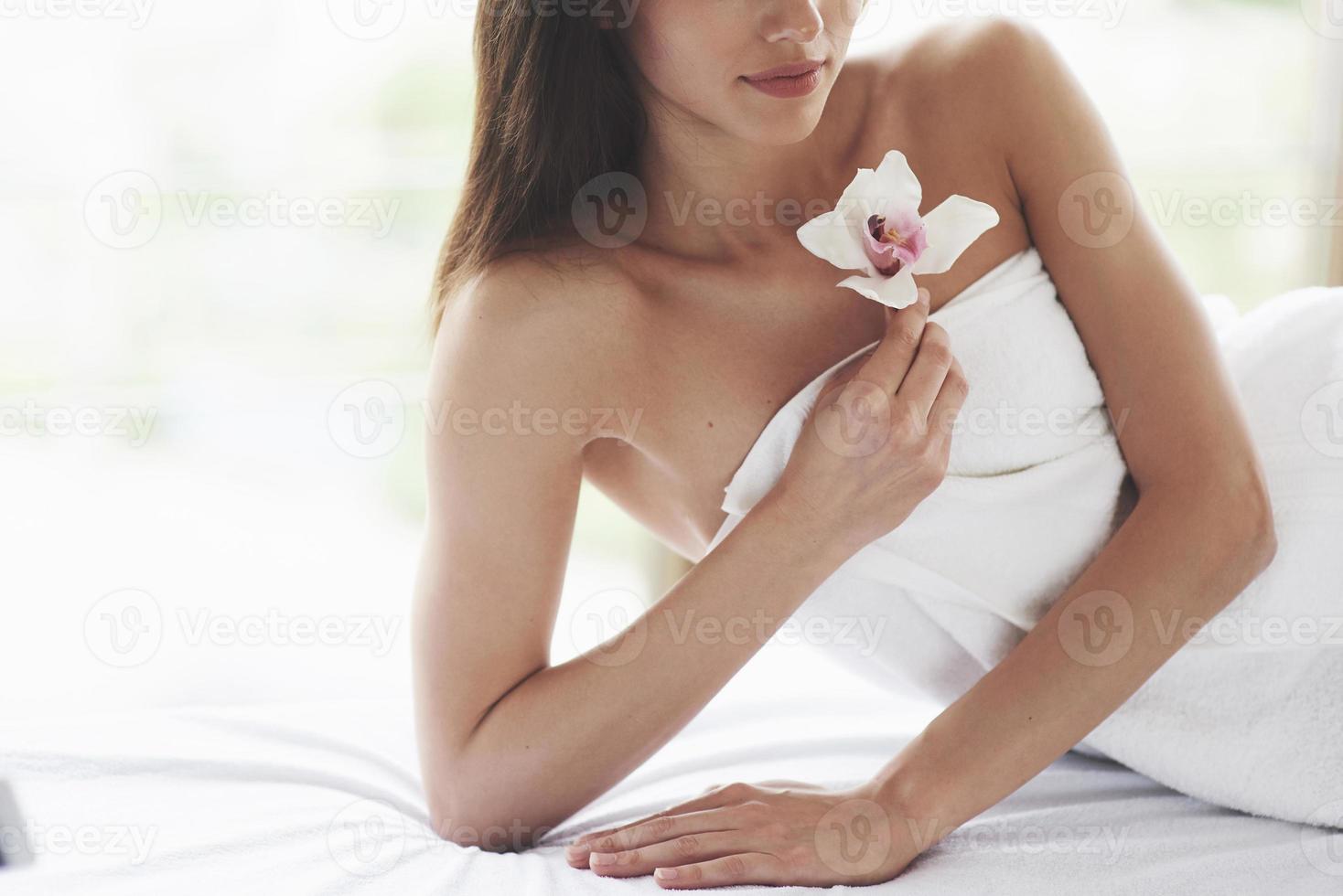 mujer de hermoso cuerpo con orquídea de flor blanca y cuidado del cuerpo. foto