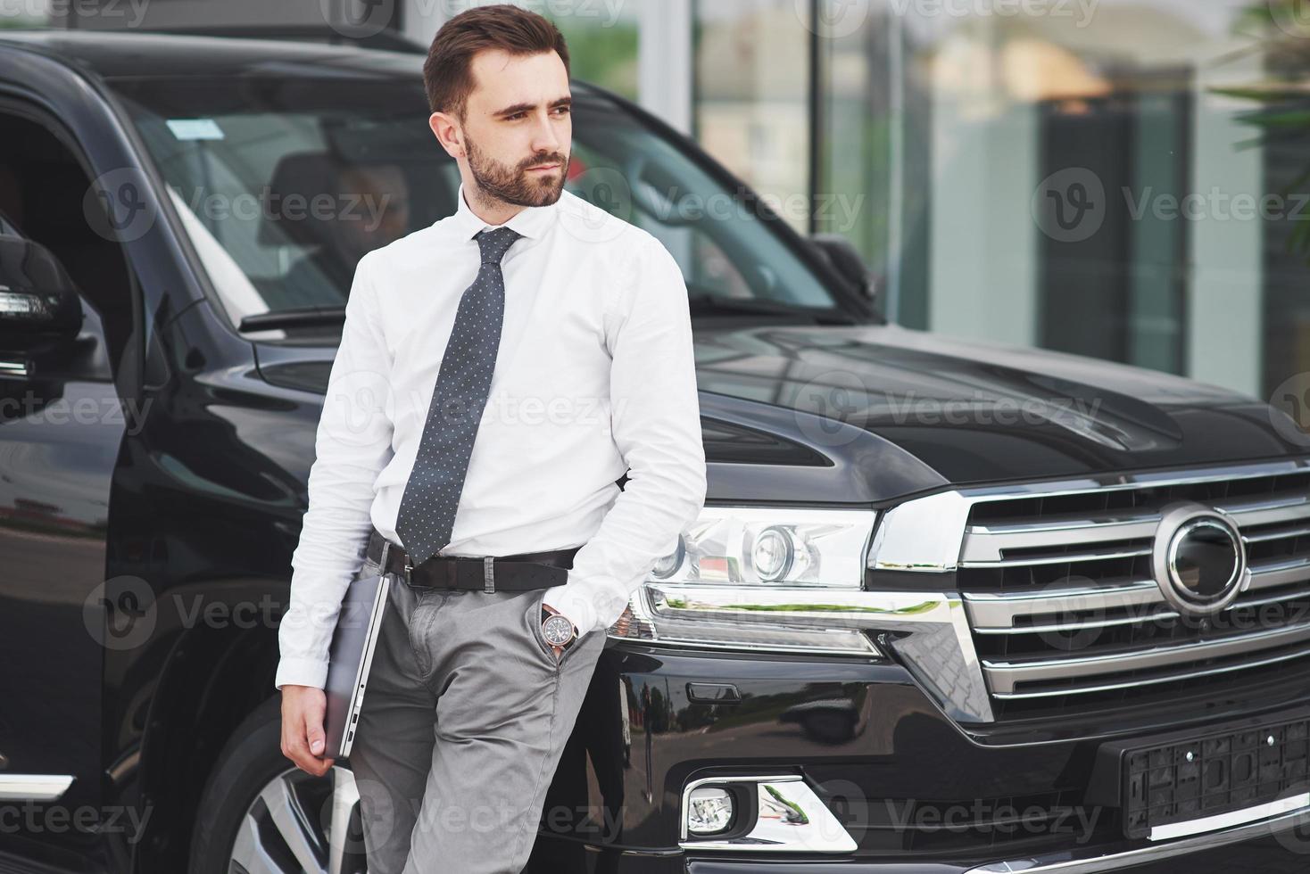 retrato de un hombre hermoso en ropa de negocios de pie afuera en la oficina. foto