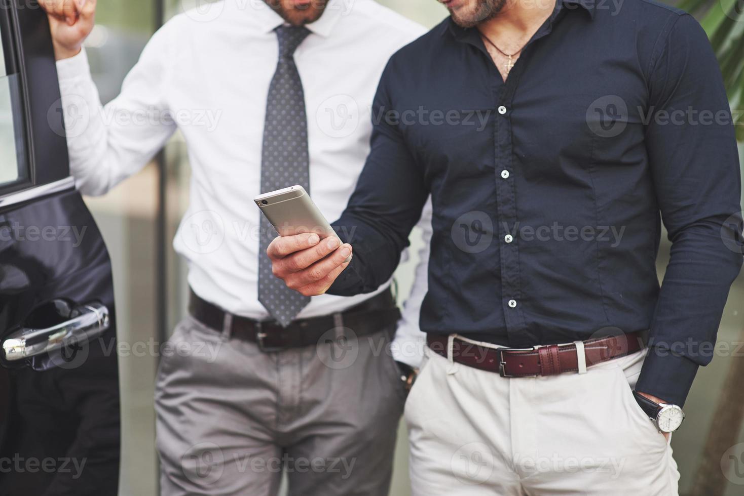 Two happy, confident young businessmen standing by the office photo