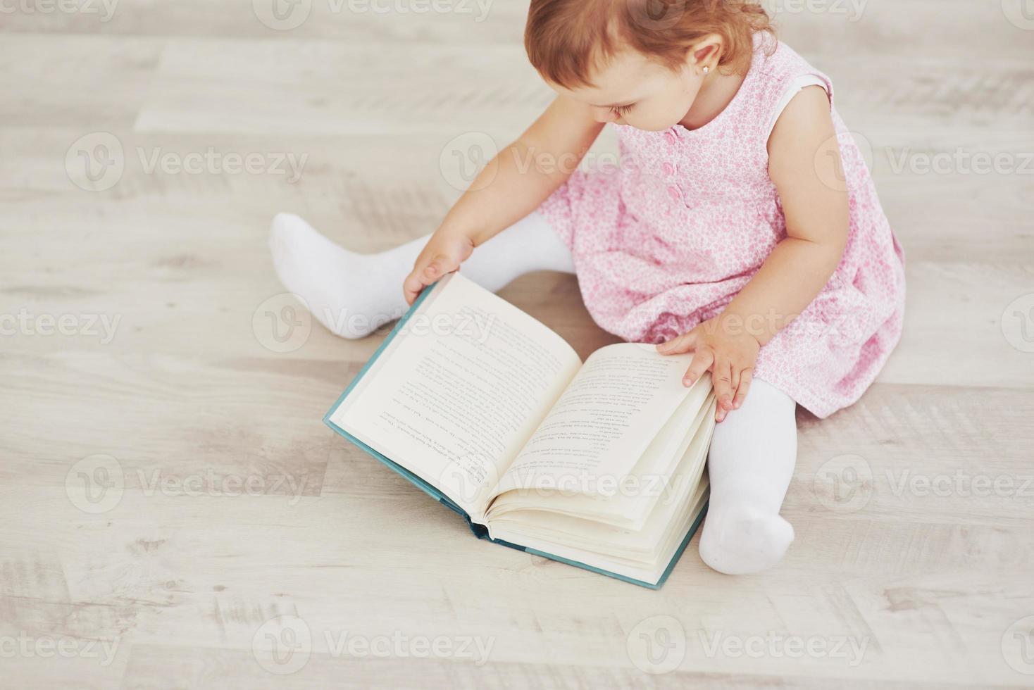Beautiful little girl read book with her favorite bear on a soft plush blanket photo