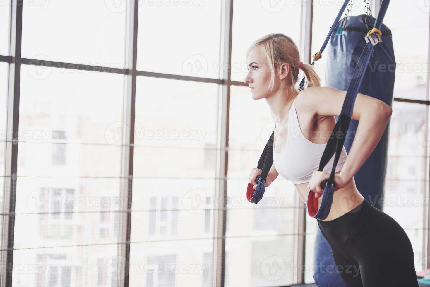 Women doing push ups training arms with trx fitness straps in the gym Concept workout healthy lifestyle sport photo