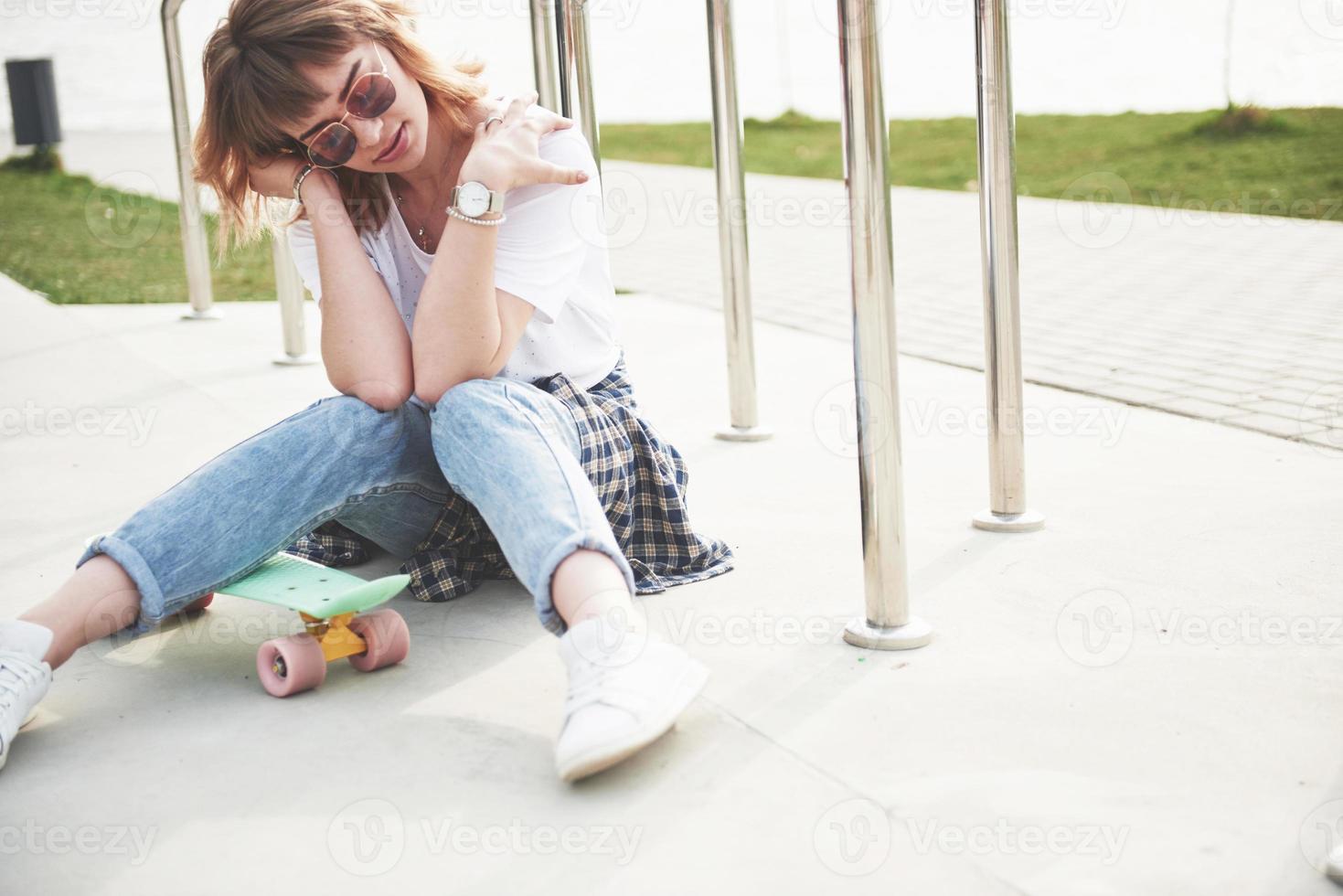 A beautiful young girl is having fun in the park, and riding a skateboard photo