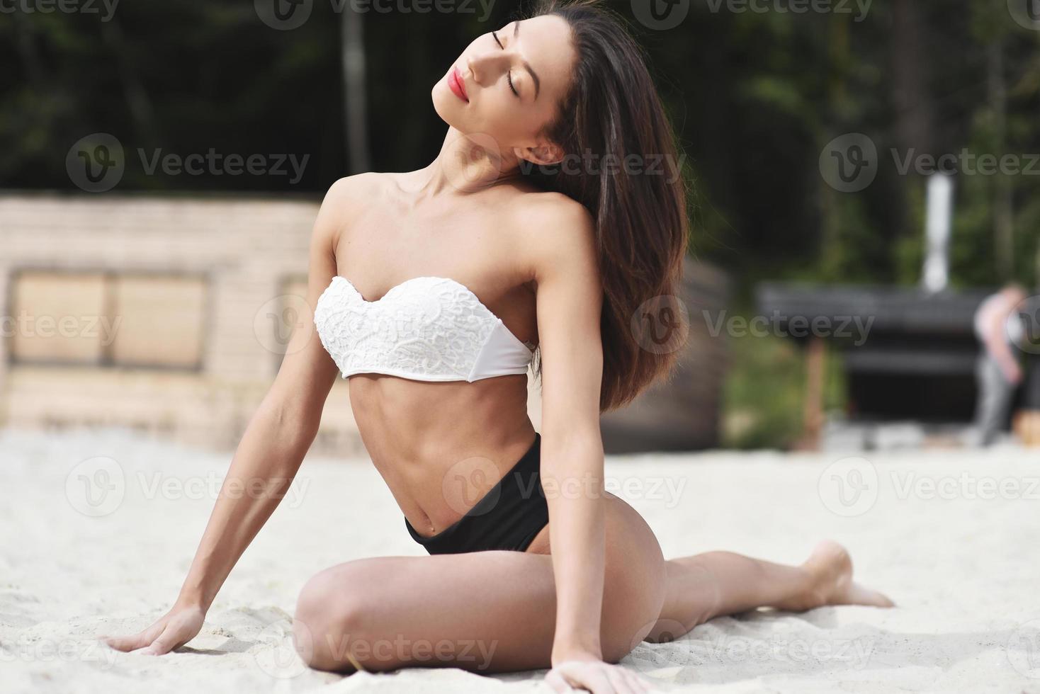 A beautiful sportswoman on the beach doing stretch marks. photo