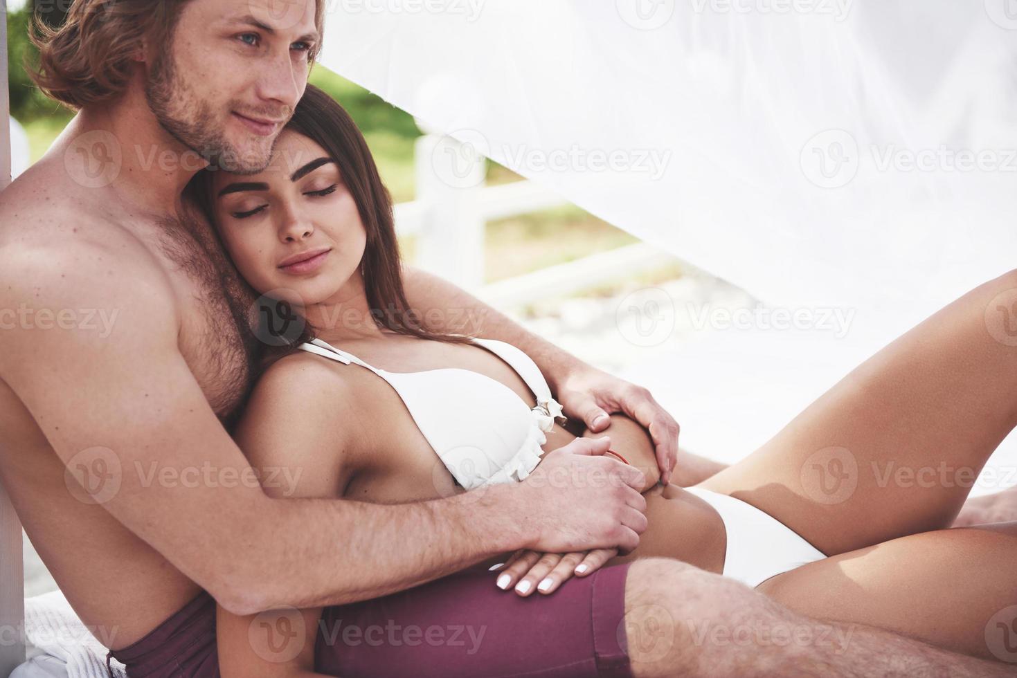 joven pareja apasionada en la arena en un día de verano en la playa. foto