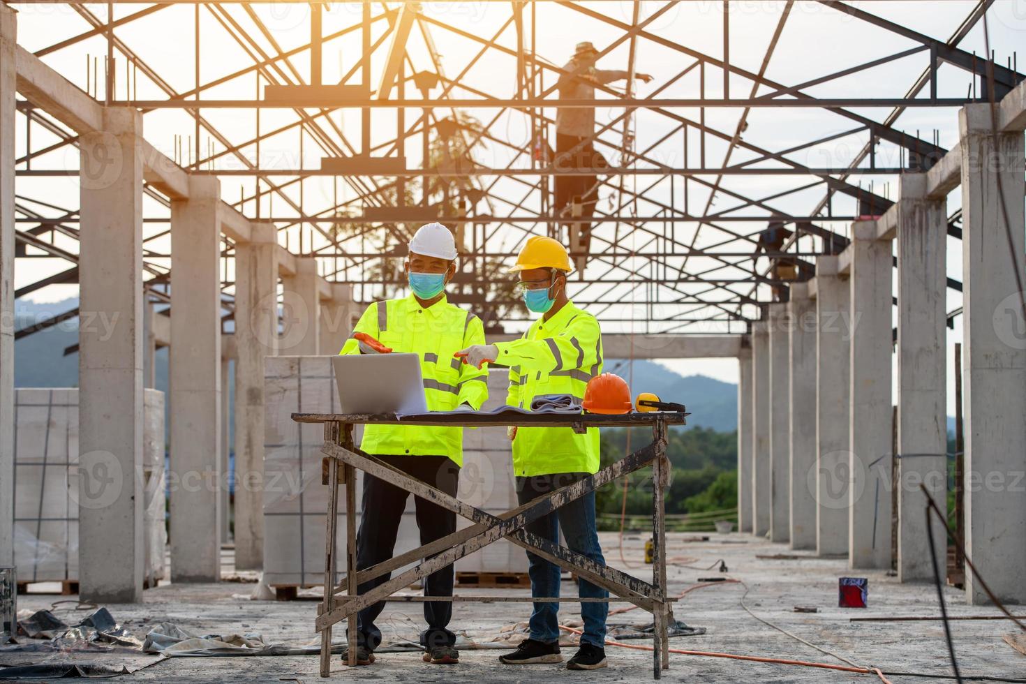 Ingeniero y supervisor trabajando juntos en el sitio de construcción y enmascarados. foto