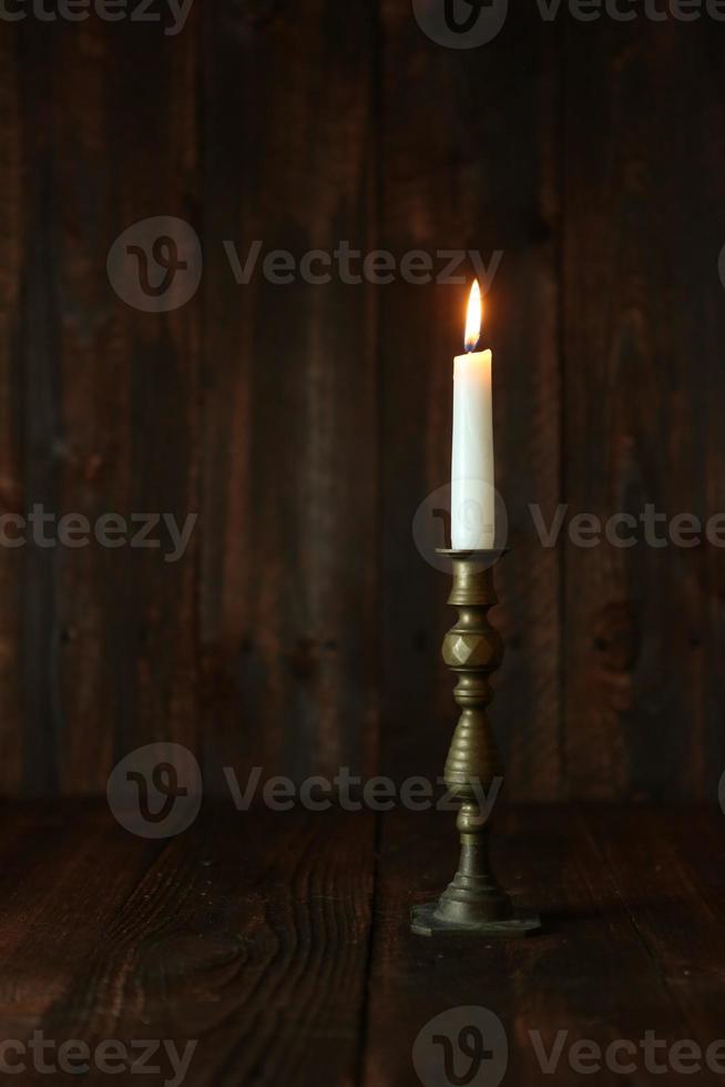 Lit Candle on an Old Wooden Rustic Background photo