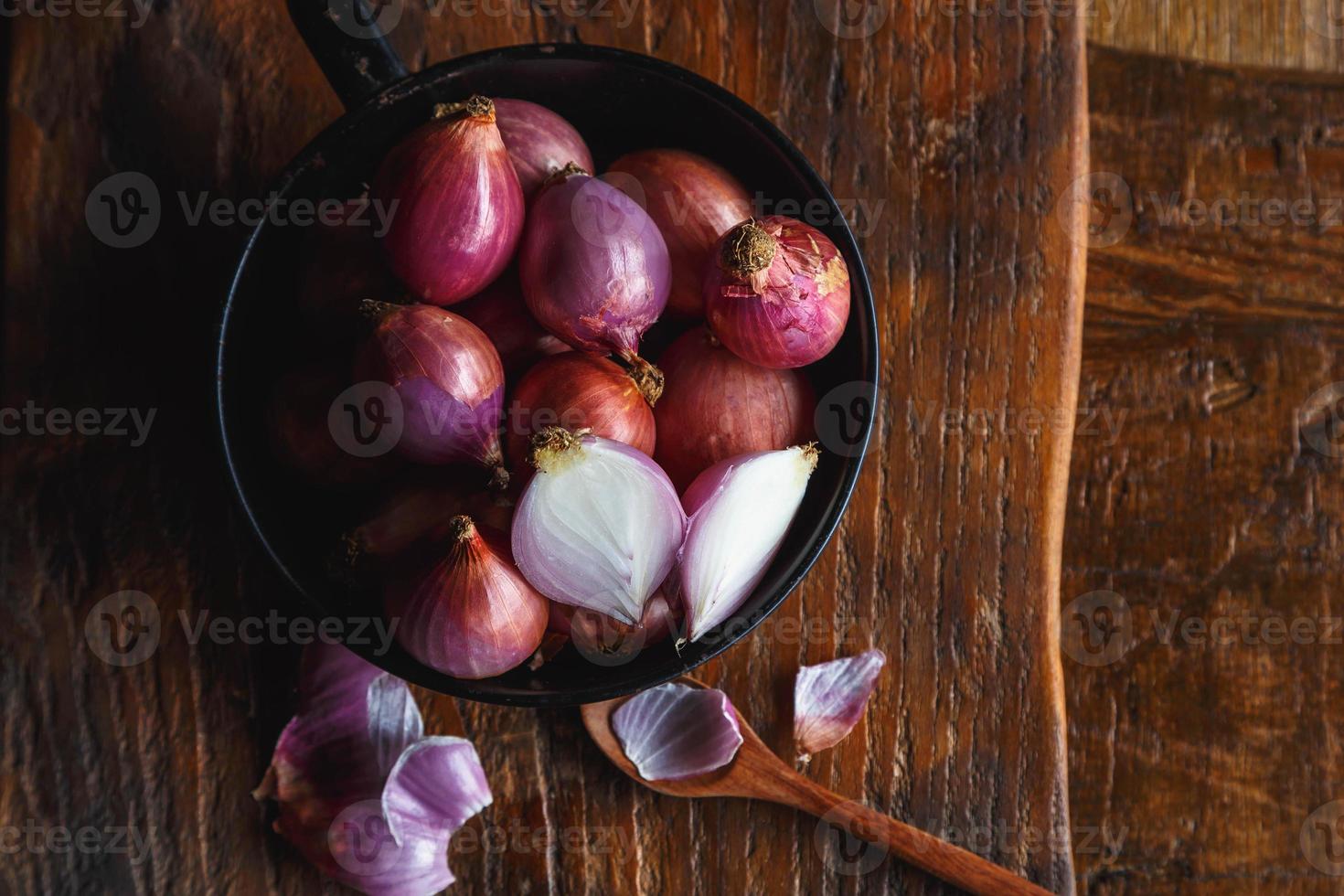 Cebollas rojas frescas en la sartén sobre la mesa de la cocina foto