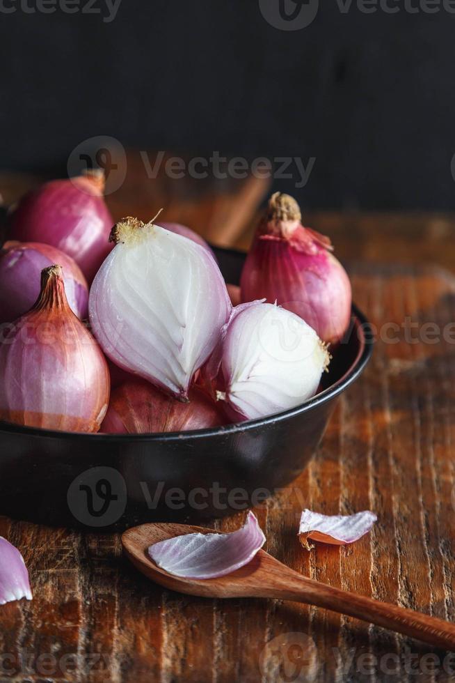 Cebollas rojas frescas en la sartén sobre la mesa de la cocina foto