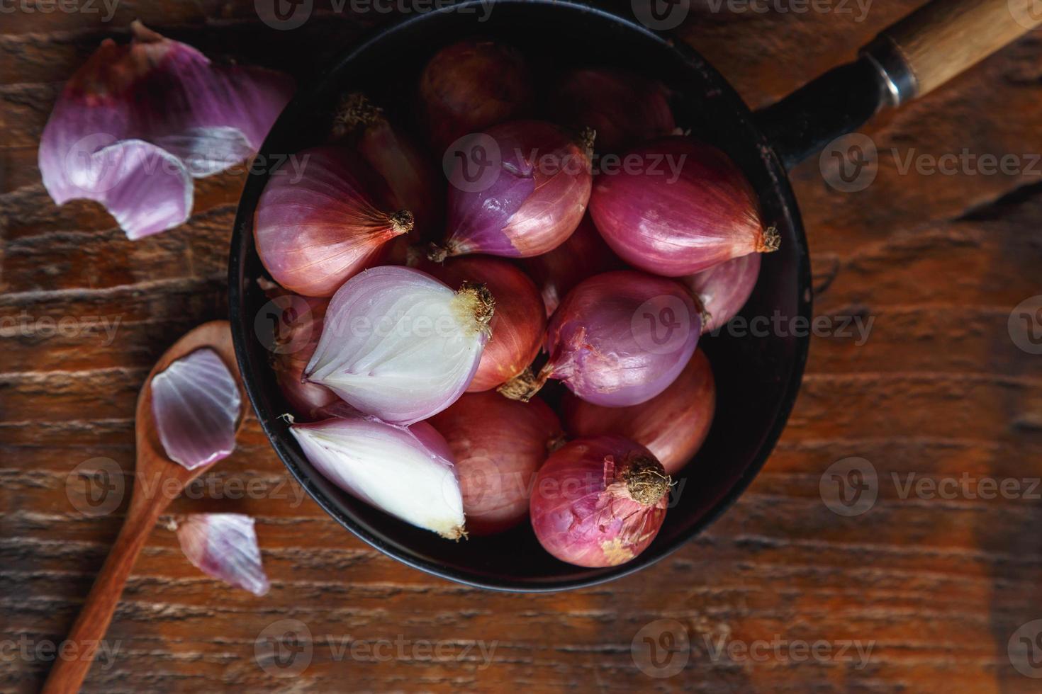 Cebollas rojas frescas en la sartén sobre la mesa de la cocina foto