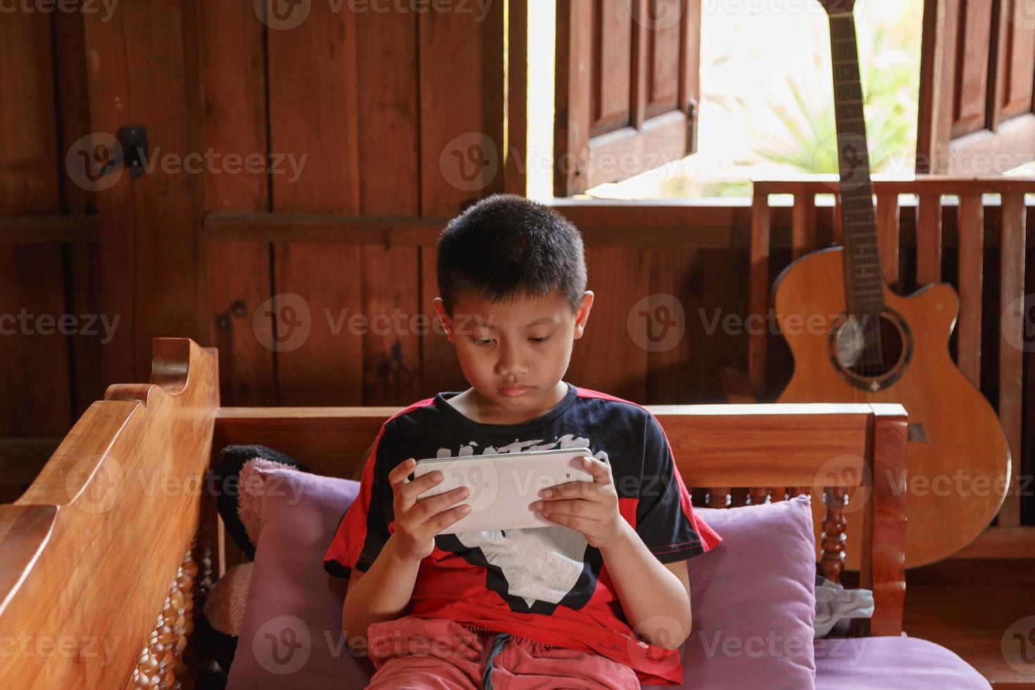 The boy was playing with the tablet at home. photo