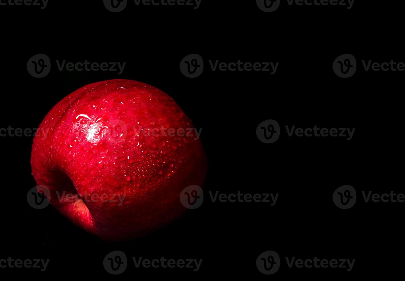 Water droplet on glossy surface of red apple on black background photo