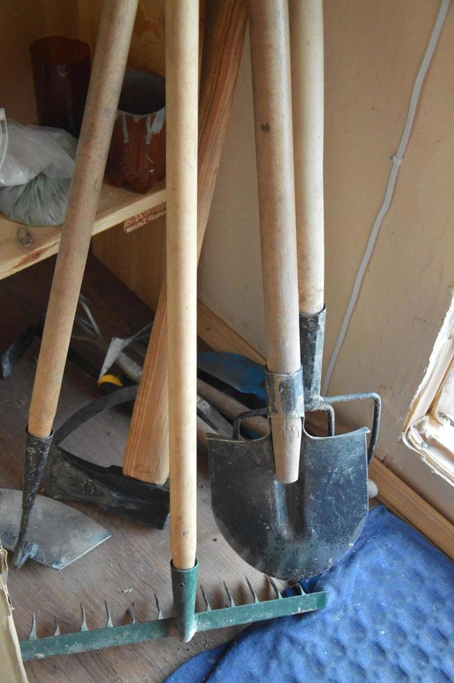 Garden tools, shovels, rakes, pitchforks are standing in the barn photo