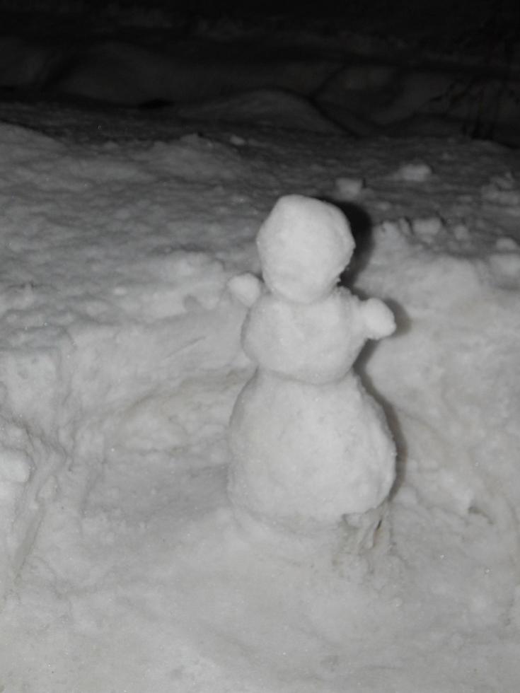 pequeño muñeco de nieve sobre fondo de nieve foto