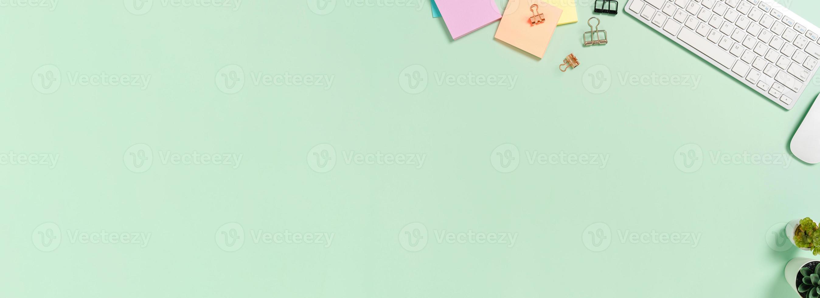 Creative flat lay photo of workspace desk. Top view office desk with keyboard, mouse and book on pastel green color background. Panoramic banner with copy space for text and Advertising area.