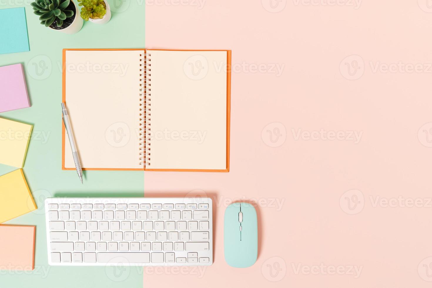 Creative flat lay photo of workspace desk. Top view office desk with keyboard, mouse and open mockup black notebook on pastel green pink color background. Top view mock up with copy space photography.