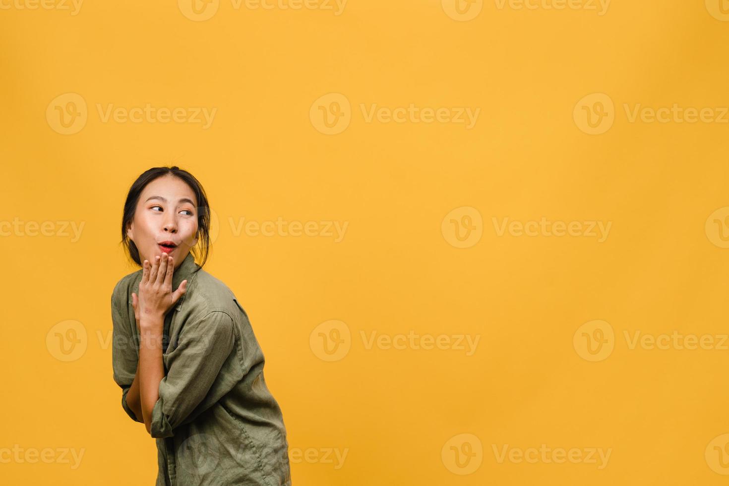 La joven dama de Asia siente felicidad con expresión positiva, alegre sorpresa funky, vestida con un paño casual aislado sobre fondo amarillo. feliz adorable mujer alegre se regocija con el éxito. expresión facial. foto