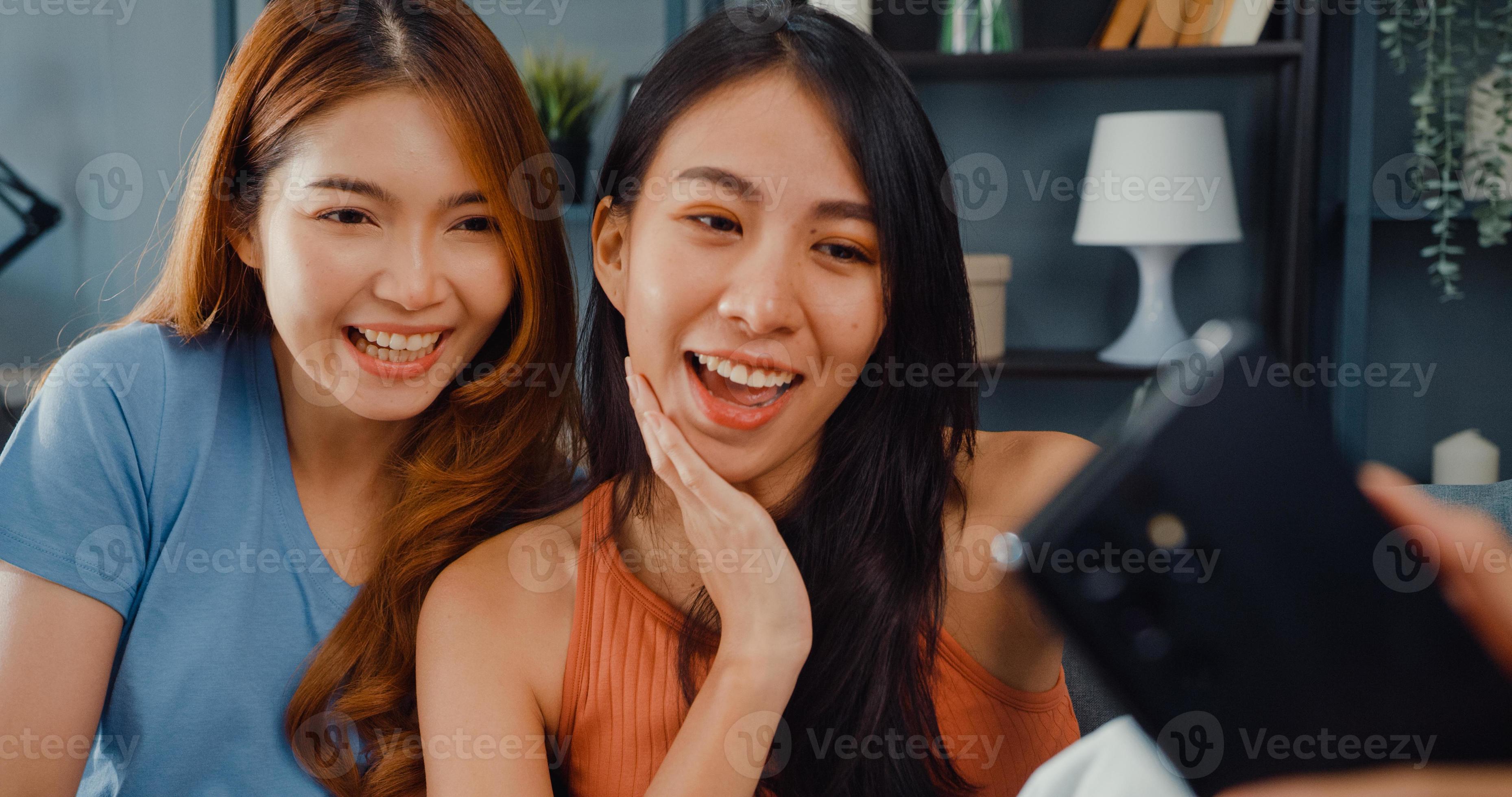 Teenager Asian women feeling happy smiling relax use smartphone video call in living room at home. Cheerful Roommate ladies video conference with friend and family, Lifestyle woman at home concept. photo