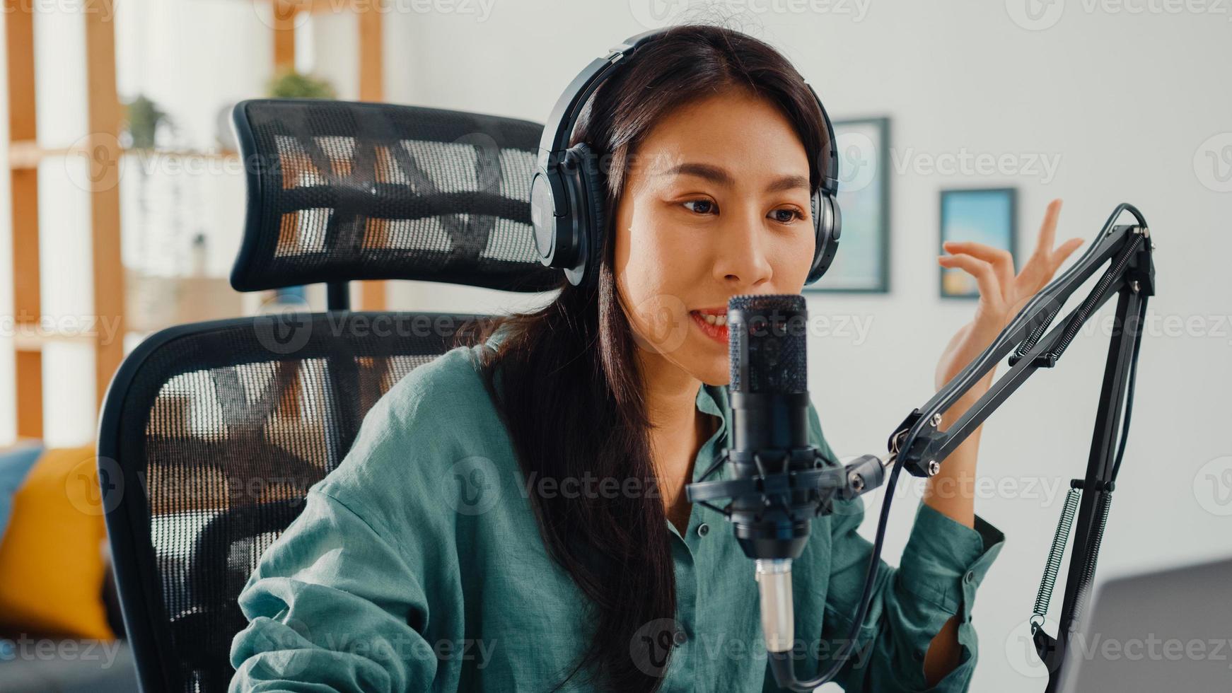 Happy asia girl record a podcast on her laptop computer with headphones and microphone talk with audience at her room. Female podcaster make audio podcast from her home studio, Stay at house concept. photo