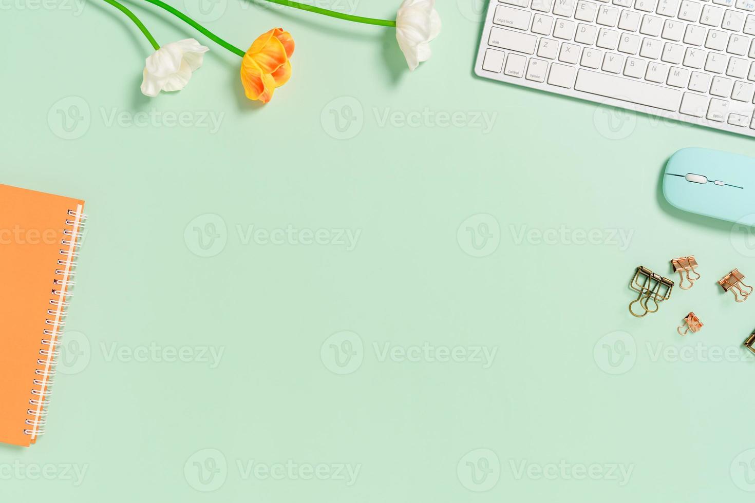 espacio de trabajo mínimo: foto creativa plana del escritorio del espacio de trabajo. escritorio de oficina de vista superior con teclado, mouse y cuaderno sobre fondo de color verde pastel. vista superior con espacio de copia, fotografía plana.