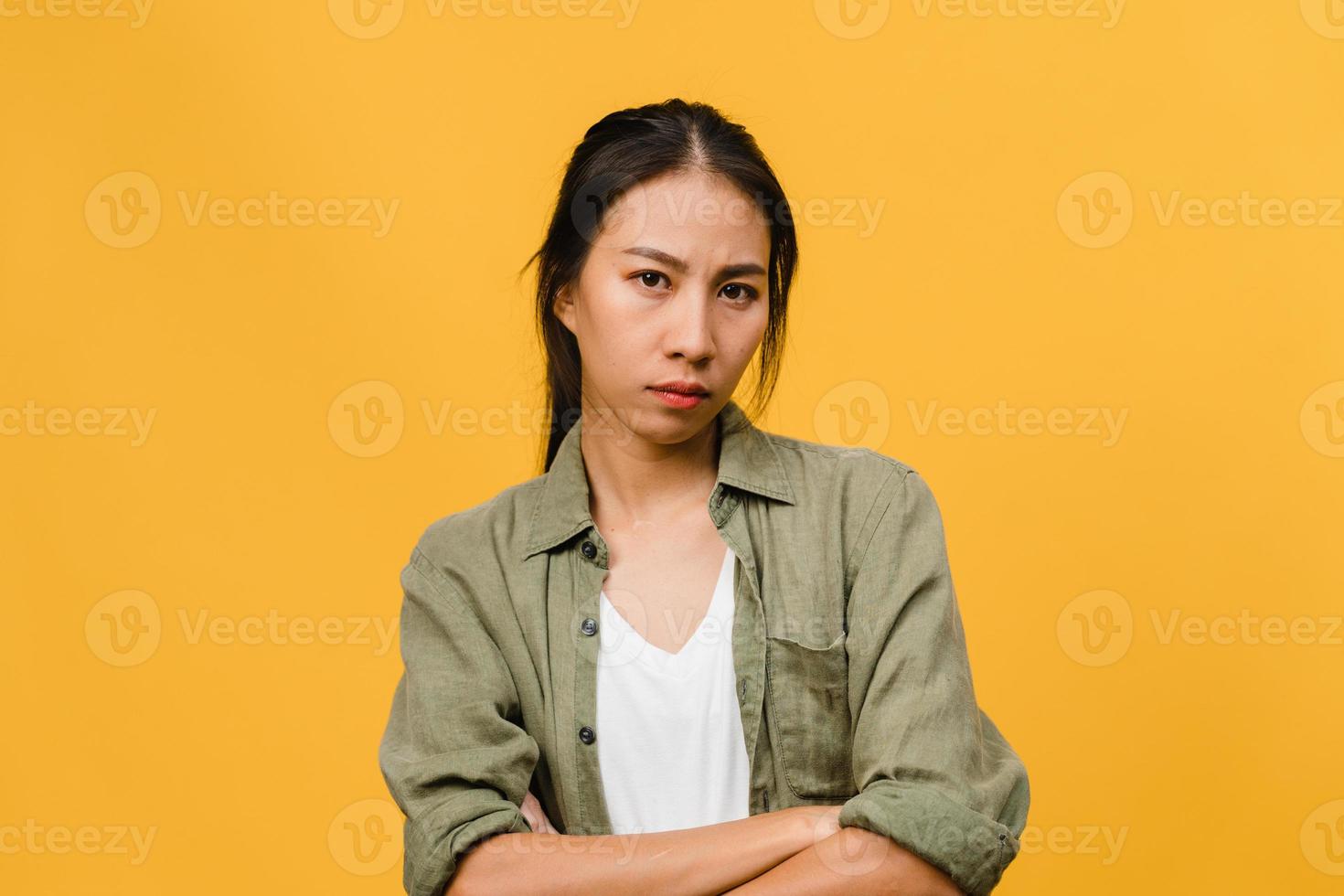 Jovencita asiática con expresión negativa, gritos emocionados, llorando enojado emocionalmente en ropa casual y mira a cámara aislada sobre fondo amarillo con espacio de copia en blanco. concepto de expresión facial foto