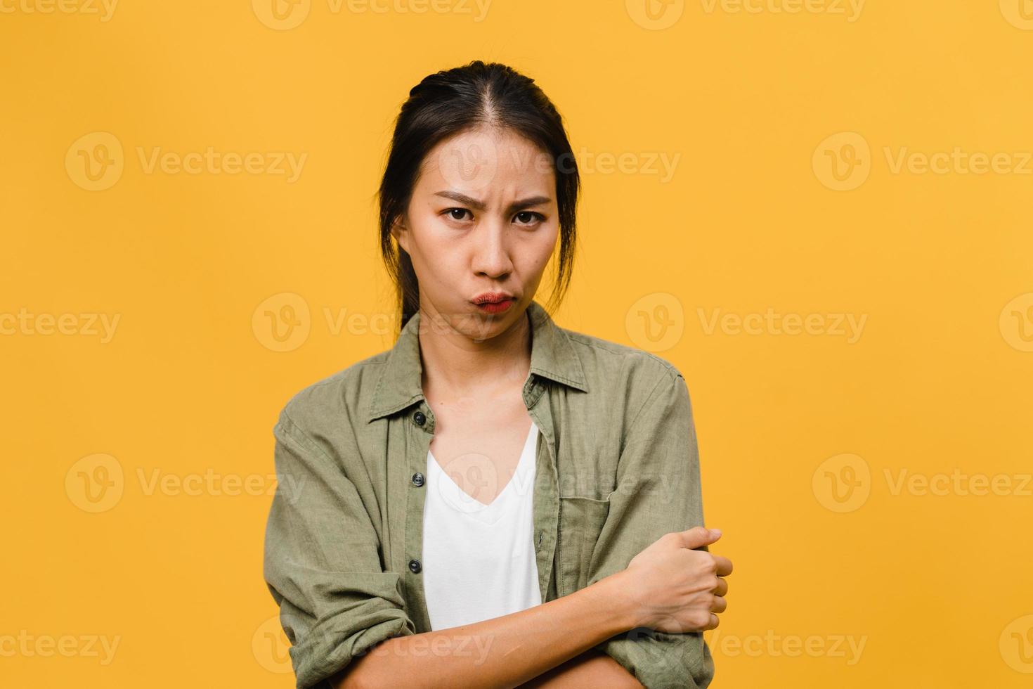 Young Asia lady with negative expression, excited screaming, crying emotional angry in casual clothing and look at camera isolated on yellow background with blank copy space. Facial expression concept photo