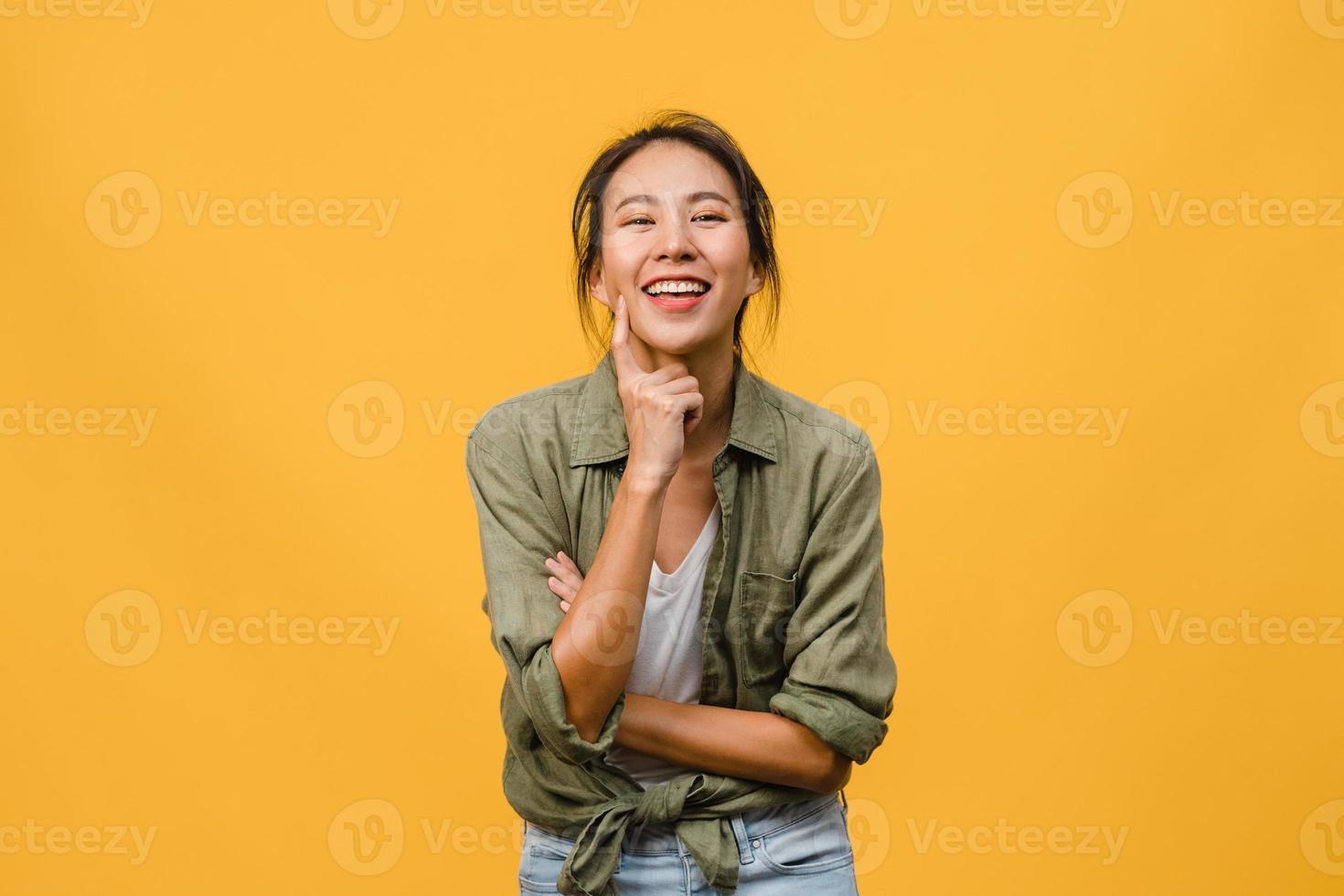 Retrato de joven asiática con expresión positiva, brazos cruzados, sonrisa amplia, vestida con ropa casual y mirando a cámara sobre fondo amarillo. feliz adorable mujer alegre se regocija con el éxito. foto