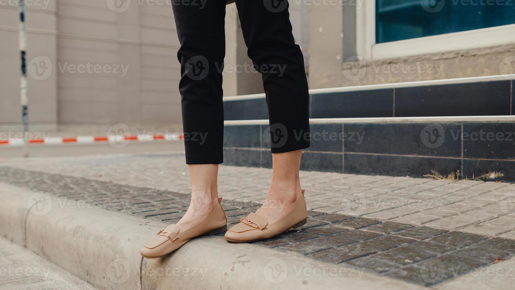 Successful young Asian business woman legs and feet detail in fashion office clothes walking through outdoors in urban modern city in the evening. Business on the go concept. photo