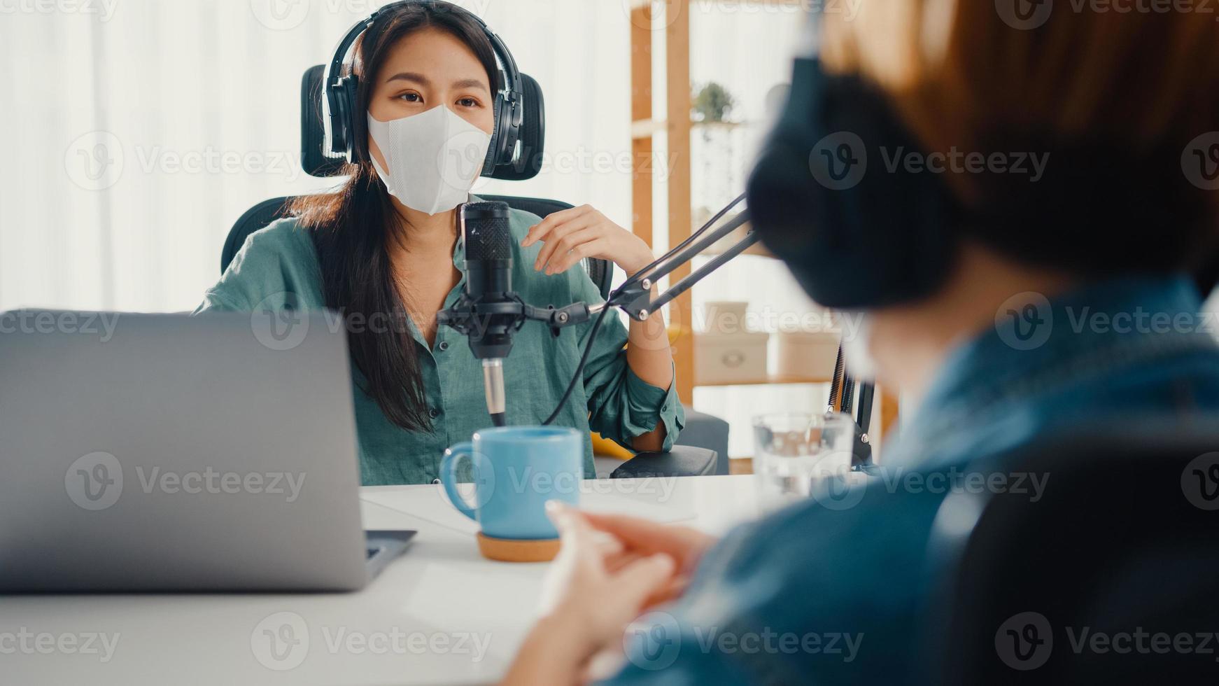 Asia girl radio host record podcast use microphone wear headphone interview guest content wear mask protect virus conversation talk and listen in her room. Podcast from home, coronavirus quarantine. photo