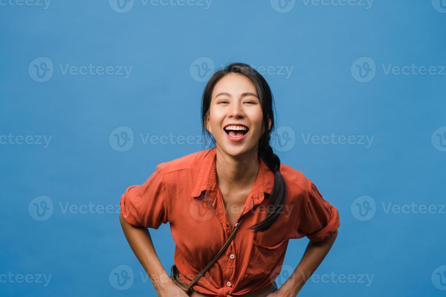 joven asiática con expresión positiva, sonrisa amplia, vestida con ropa informal y mirando a cámara sobre fondo azul. feliz adorable mujer alegre se regocija con el éxito. concepto de expresión facial. foto