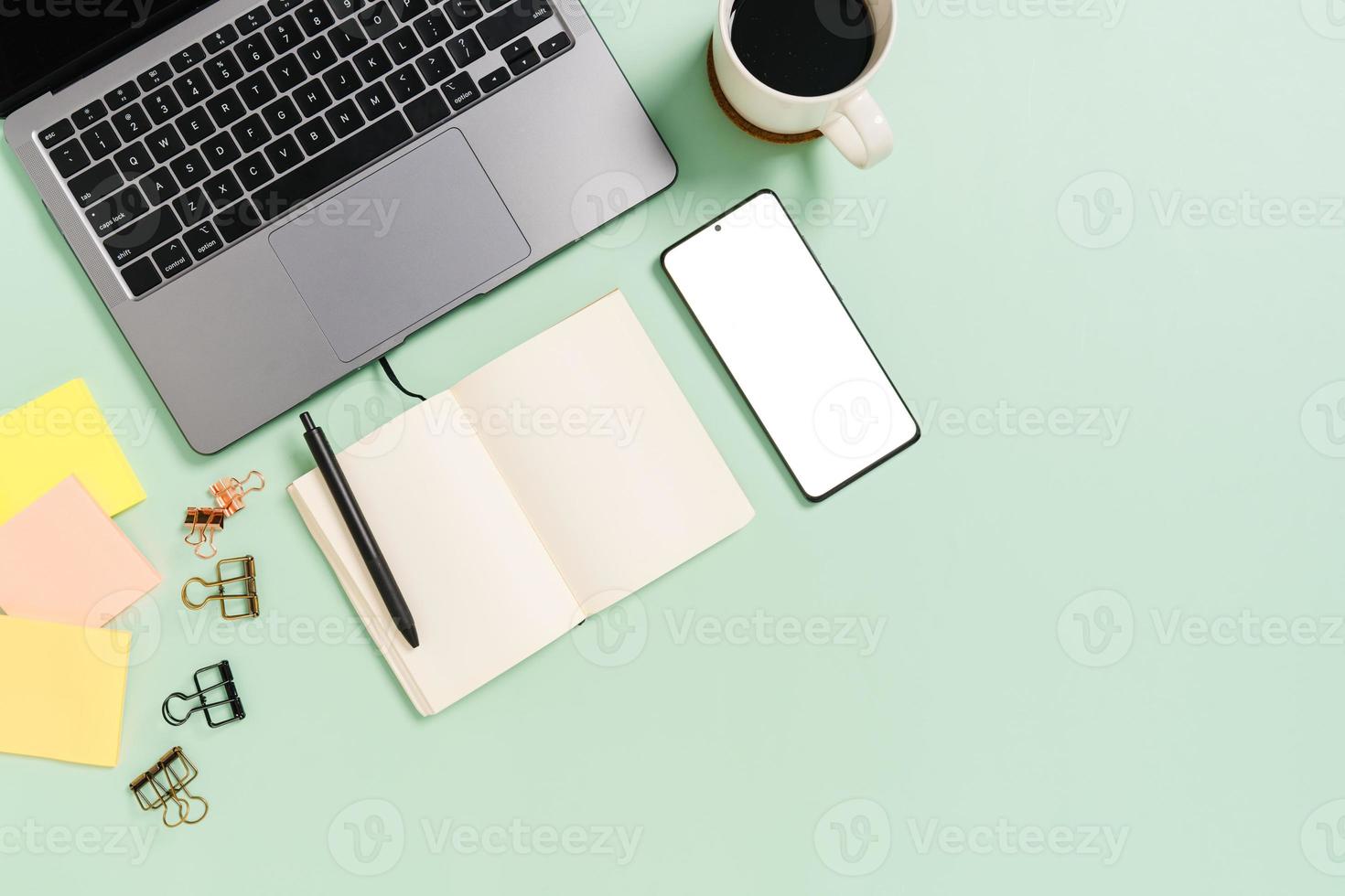 Foto creativa plana del escritorio del espacio de trabajo. escritorio de oficina de vista superior con computadora portátil, taza de café y cuaderno negro de maqueta abierta sobre fondo de color verde pastel. vista superior maqueta con fotografía de espacio de copia.