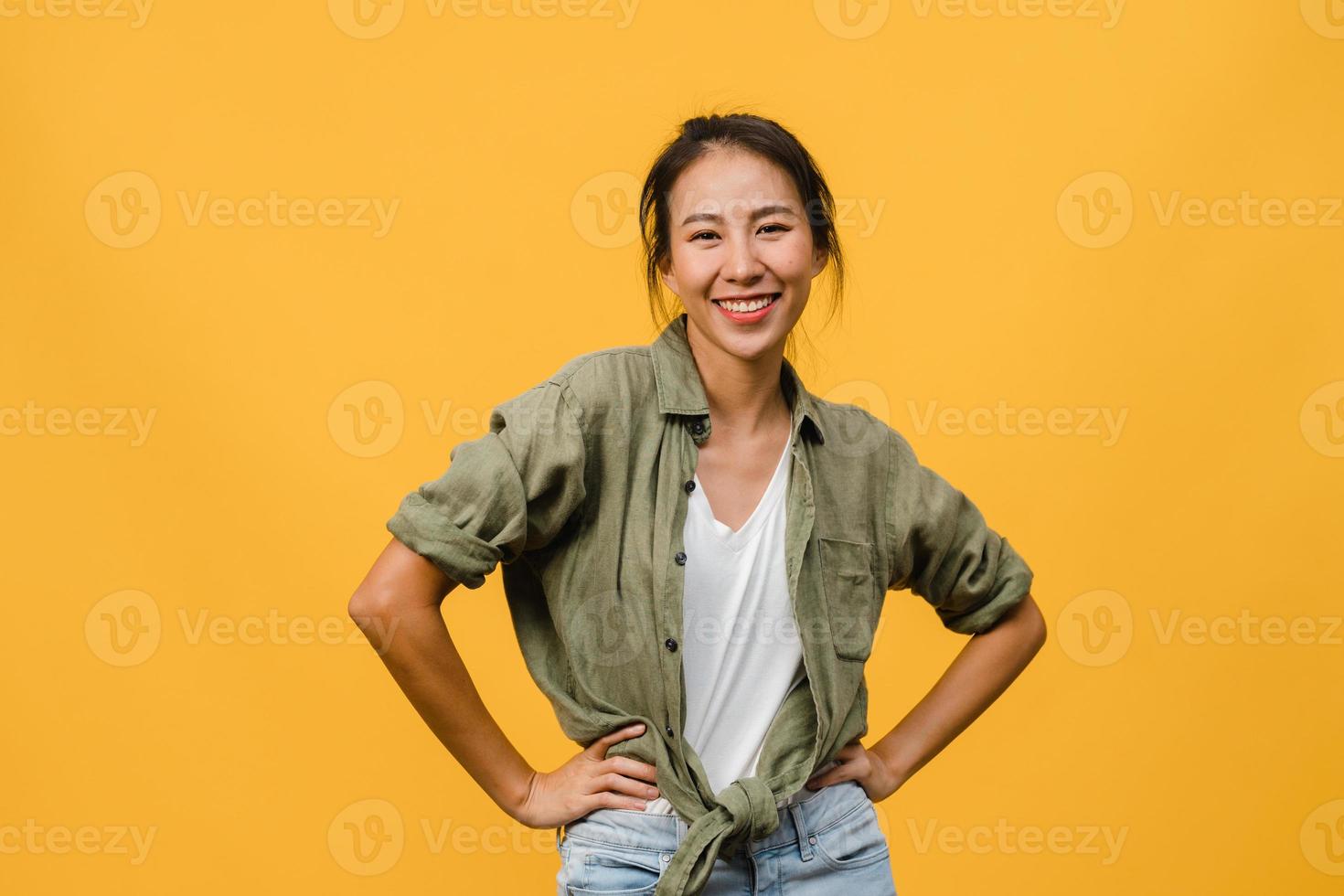 Young Asia lady with positive expression, smile broadly, dressed in casual clothing and looking at camera over yellow background. Happy adorable glad woman rejoices success. Facial expression concept. photo